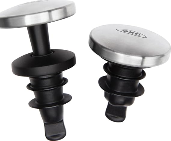 Dos tapones OXO con cuerpo negro de silicona y parte superior plateada, uno extendido