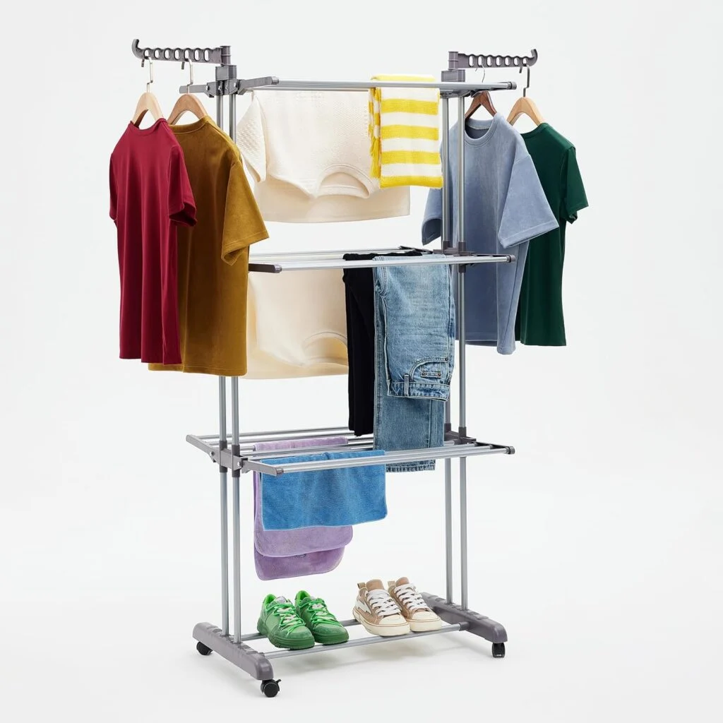 Tendedero Amazon Basics tipo torre plateado de cuatro niveles con alas y prendas colgadas