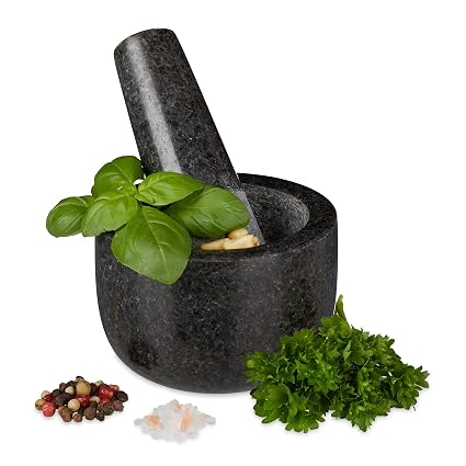 Mortero pequeño de granito negro Relaxdays con mano y hierbas alrededor